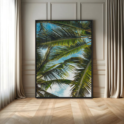 Looking up at lush green palm leaves against a bright blue sky, creating a tropical and relaxing coastal aesthetic.