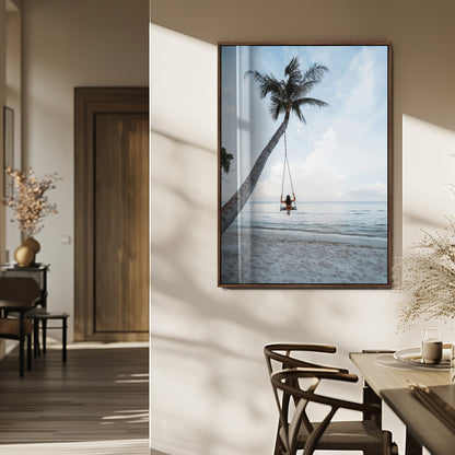 Wall art of a girl on a swing hanging from a palm tree over calm ocean waters, perfect for tropical or minimalist coastal decor.