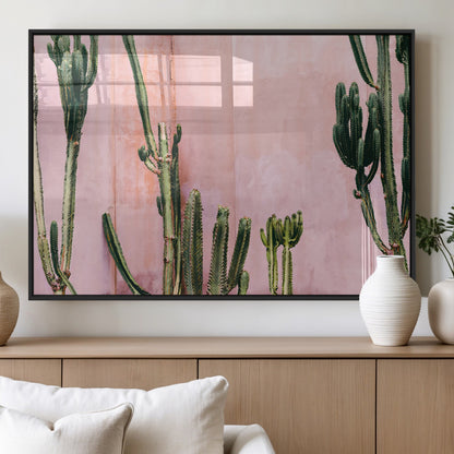 Framed canvas of tall green cacti against a soft pink wall, ideal for modern desert or colorful southwest-inspired home decor.