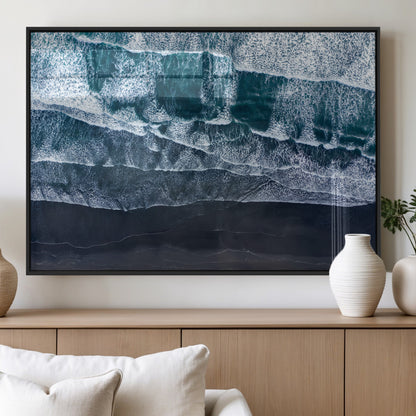 Canvas of aerial ocean waves crashing onto a black sand beach in moody tones, ideal for modern coastal or minimalist home decor.
