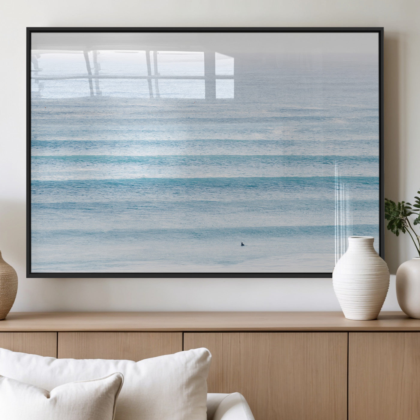 Minimalist ocean view with soft blue waves and a lone surfer, creating a serene and airy coastal aesthetic, perfect for tranquil home decor.