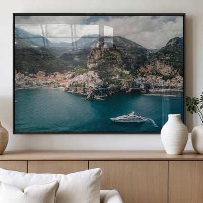 Aerial view of Amalfi Coast, Italy, with colorful hillside houses, lush green mountains, and a luxury yacht sailing in turquoise waters.