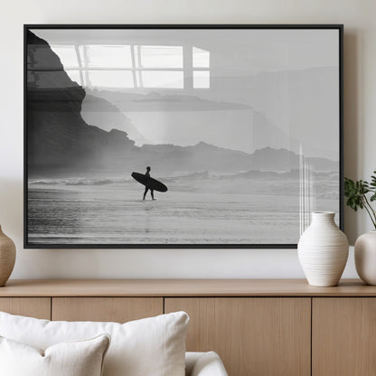 A lone surfer walking along a misty beach with cliffs in the background, carrying their board, capturing a serene and minimal ocean moment.