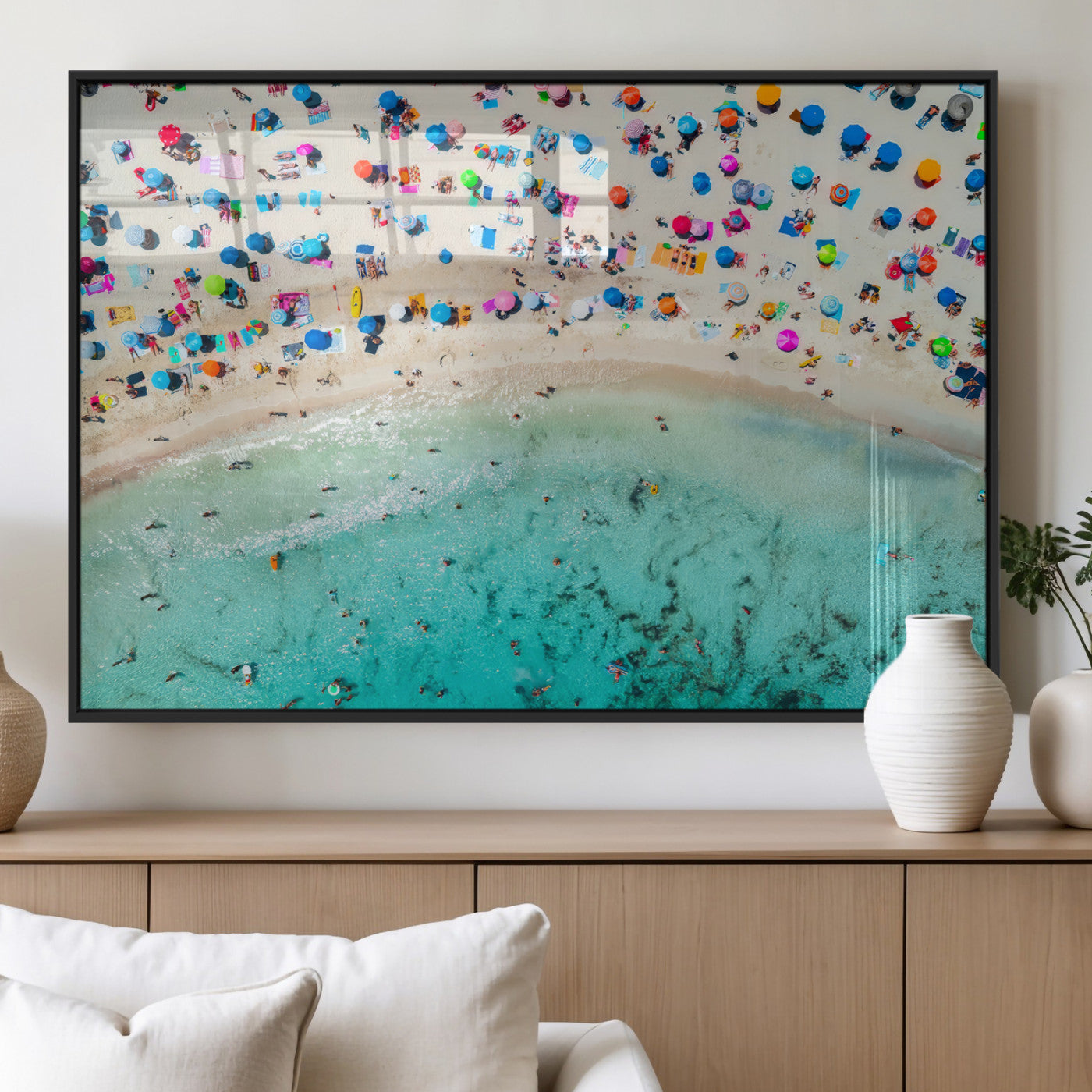 Aerial view of a vibrant beach filled with colorful umbrellas and people enjoying the turquoise ocean, capturing a lively summer vacation scene.