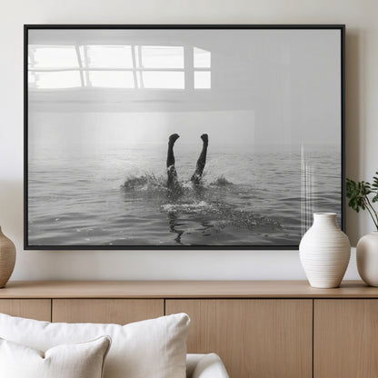 A black and white minimalist water scene capturing a playful splash as a swimmer dives upside down, creating a carefree and artistic aquatic aesthetic.