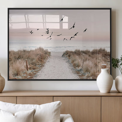 A peaceful coastal pathway leading to the ocean, with birds flying across a soft pastel sky, creating a calm and scenic beach atmosphere.