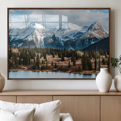 Framed canvas of snowy mountain peaks with pine forest and alpine lake, perfect for winter cabin or wilderness-inspired home decor.