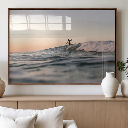 Framed canvas of a female surfer balancing on a wave at sunset, perfect for serene surf or ocean-inspired coastal decor.