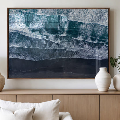Canvas of aerial ocean waves crashing onto a black sand beach in moody tones, ideal for modern coastal or minimalist home decor.