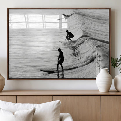 Black and white photo of surfers riding waves in a moody, high-contrast scene, ideal for modern coastal or surf-inspired home decor.