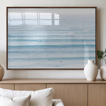 Minimalist ocean view with soft blue waves and a lone surfer, creating a serene and airy coastal aesthetic, perfect for tranquil home decor.