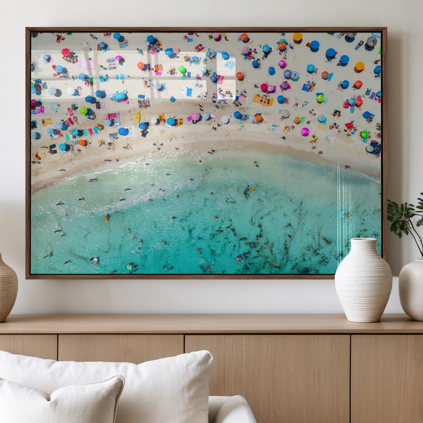 Aerial view of a vibrant beach filled with colorful umbrellas and people enjoying the turquoise ocean, capturing a lively summer vacation scene.