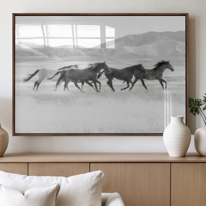 A black and white image of wild horses running freely across an open grassland, capturing the power and beauty of untamed nature in a rustic western setting.