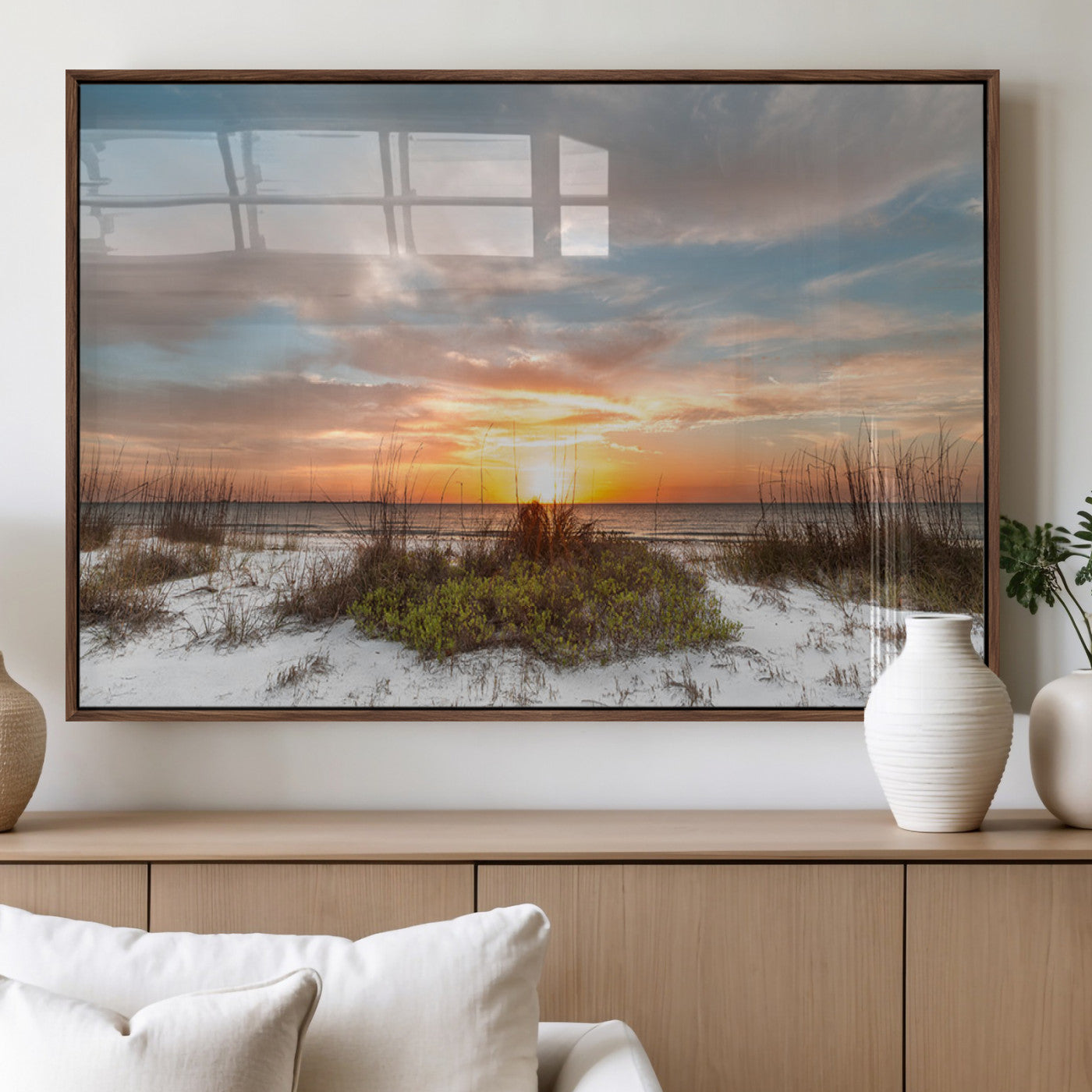 A tranquil beach scene featuring golden sunset hues over the water, with grasses in the foreground and a peaceful, serene atmosphere.