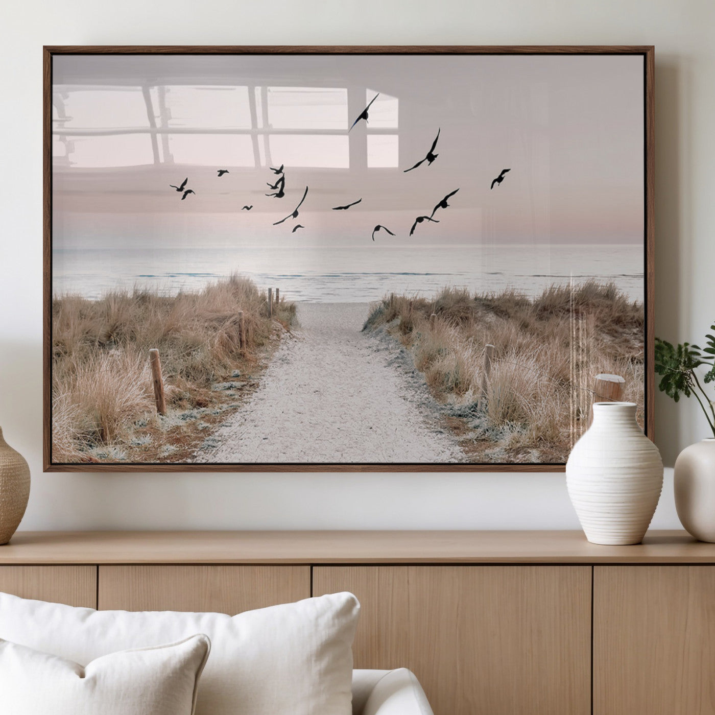 A peaceful coastal pathway leading to the ocean, with birds flying across a soft pastel sky, creating a calm and scenic beach atmosphere.