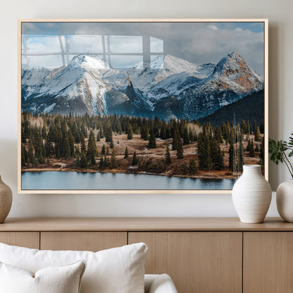 Framed canvas of snowy mountain peaks with pine forest and alpine lake, perfect for winter cabin or wilderness-inspired home decor.