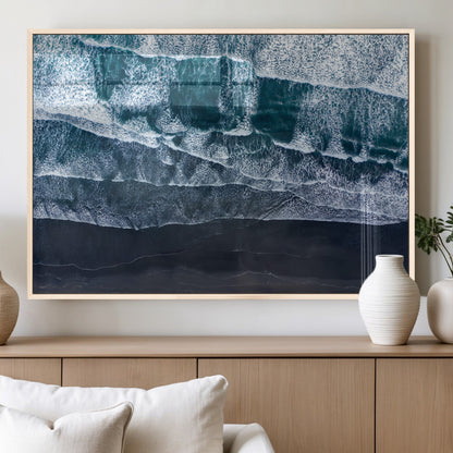 Canvas of aerial ocean waves crashing onto a black sand beach in moody tones, ideal for modern coastal or minimalist home decor.