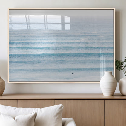 Minimalist ocean view with soft blue waves and a lone surfer, creating a serene and airy coastal aesthetic, perfect for tranquil home decor.