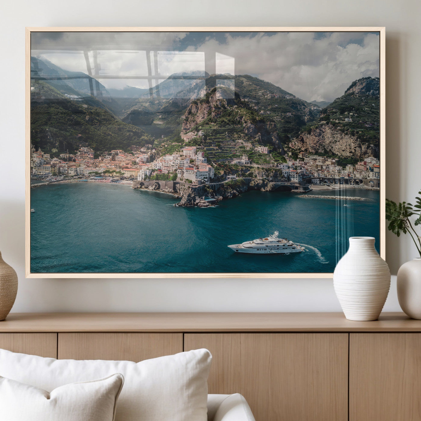 Aerial view of Amalfi Coast, Italy, with colorful hillside houses, lush green mountains, and a luxury yacht sailing in turquoise waters.