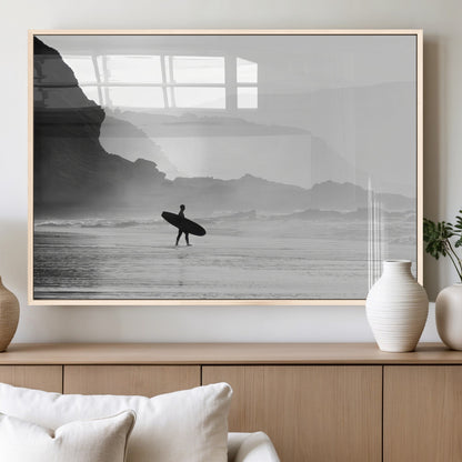 A lone surfer walking along a misty beach with cliffs in the background, carrying their board, capturing a serene and minimal ocean moment.