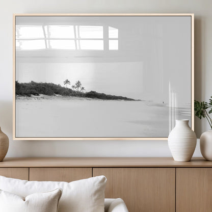 A black and white minimalist coastal scene with a vast open beach, distant palm trees, and a lone figure walking along the shoreline, evoking serenity and solitude.