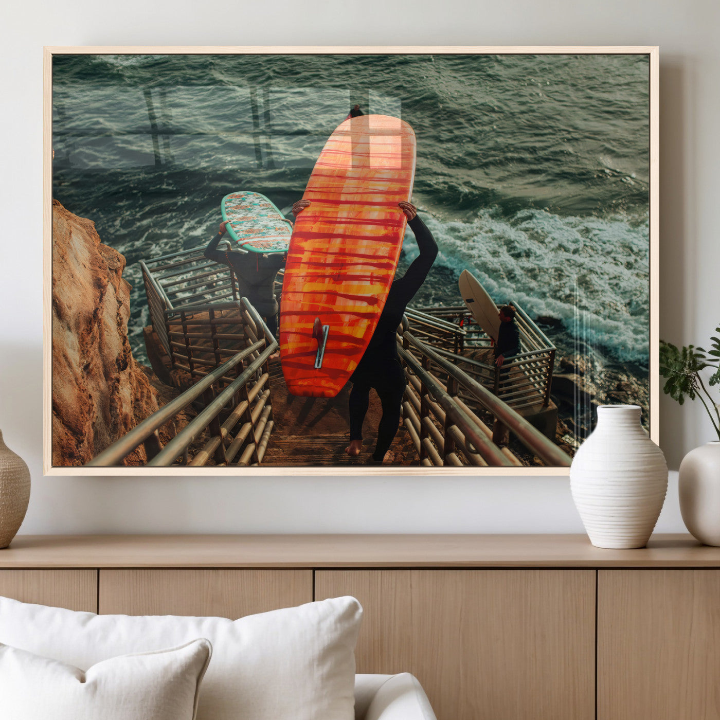 A surfer carrying a bold orange surfboard down a rugged staircase toward the ocean, bathed in golden hour light, capturing the energy of coastal adventure.