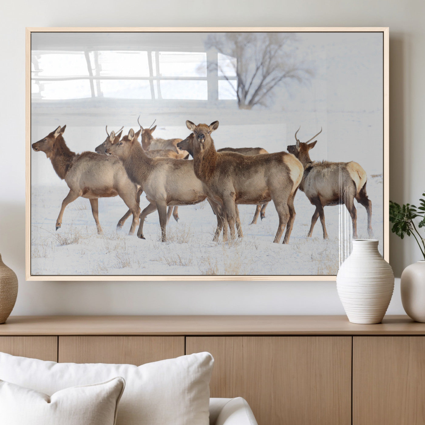 A group of elk standing on snowy terrain with a tree in the background, perfect for rustic or lodge-style winter wall decor.