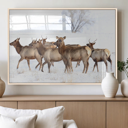 A group of elk standing on snowy terrain with a tree in the background, perfect for rustic or lodge-style winter wall decor.