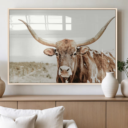 A Texas longhorn bull with wide horns, standing in a dry field under soft light, ideal for rustic farmhouse or western-themed interiors.