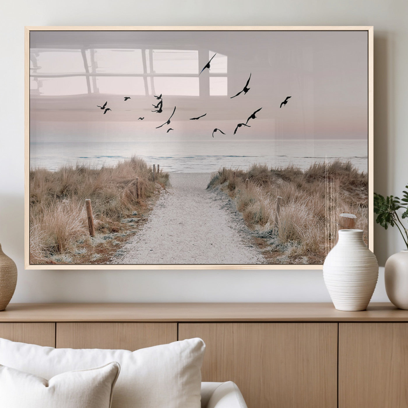 A peaceful coastal pathway leading to the ocean, with birds flying across a soft pastel sky, creating a calm and scenic beach atmosphere.