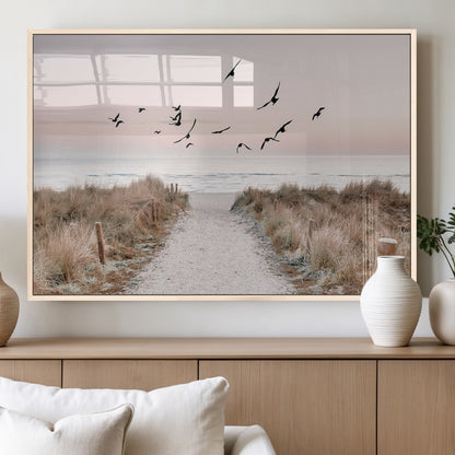 A peaceful coastal pathway leading to the ocean, with birds flying across a soft pastel sky, creating a calm and scenic beach atmosphere.