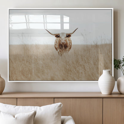 Texas Longhorn bull standing alone in dry grass with neutral tones, ideal for rustic western or cowboy-themed wall decor.