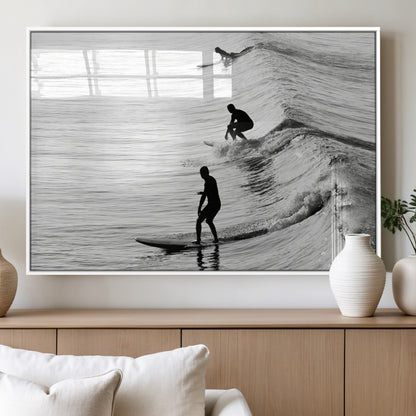 Black and white photo of surfers riding waves in a moody, high-contrast scene, ideal for modern coastal or surf-inspired home decor.