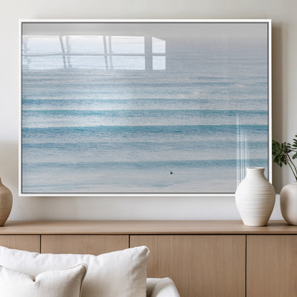 Minimalist ocean view with soft blue waves and a lone surfer, creating a serene and airy coastal aesthetic, perfect for tranquil home decor.