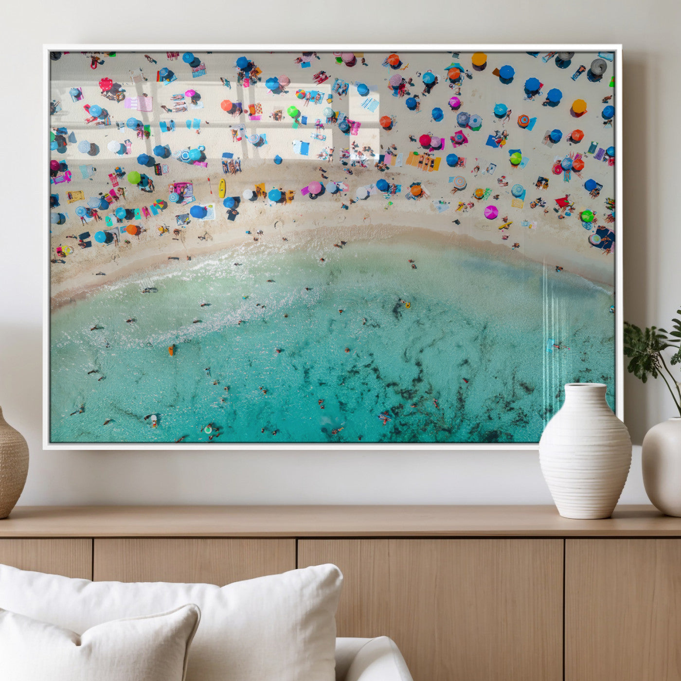 Aerial view of a vibrant beach filled with colorful umbrellas and people enjoying the turquoise ocean, capturing a lively summer vacation scene.
