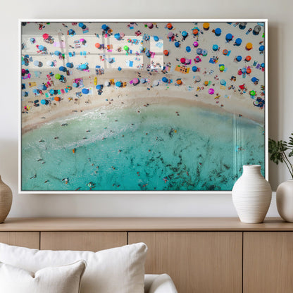 Aerial view of a vibrant beach filled with colorful umbrellas and people enjoying the turquoise ocean, capturing a lively summer vacation scene.