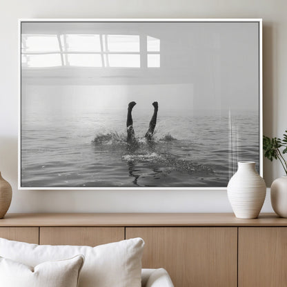A black and white minimalist water scene capturing a playful splash as a swimmer dives upside down, creating a carefree and artistic aquatic aesthetic.