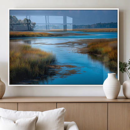 A peaceful marshland scene with calm blue water reflecting the surrounding grasses and trees, capturing the beauty of nature in a serene landscape.