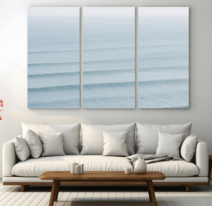 Framed canvas of repeating ocean waves with a distant solo surfer, ideal for minimalist ocean or calm coastal wall decor.