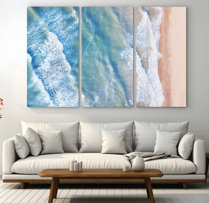 Aerial photo of soft blue waves meeting sandy shore, perfect for modern coastal or beach-themed decor with a light and tranquil aesthetic.
