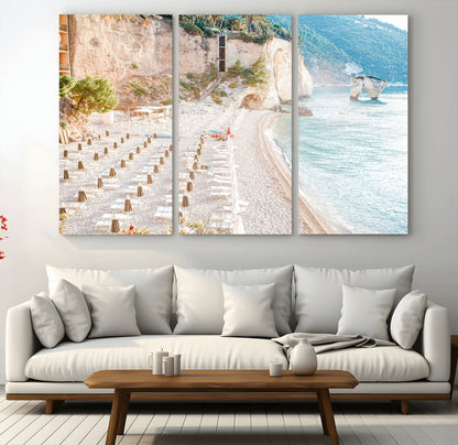Wall art of a calm Mediterranean beach with rows of sun loungers and umbrellas in soft pastel tones, perfect for light coastal or vacation-themed decor.