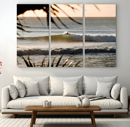 Photo of a surfer riding a golden hour wave at sunset, with tropical tones and dreamy light, perfect for tropical boho or coastal home decor.