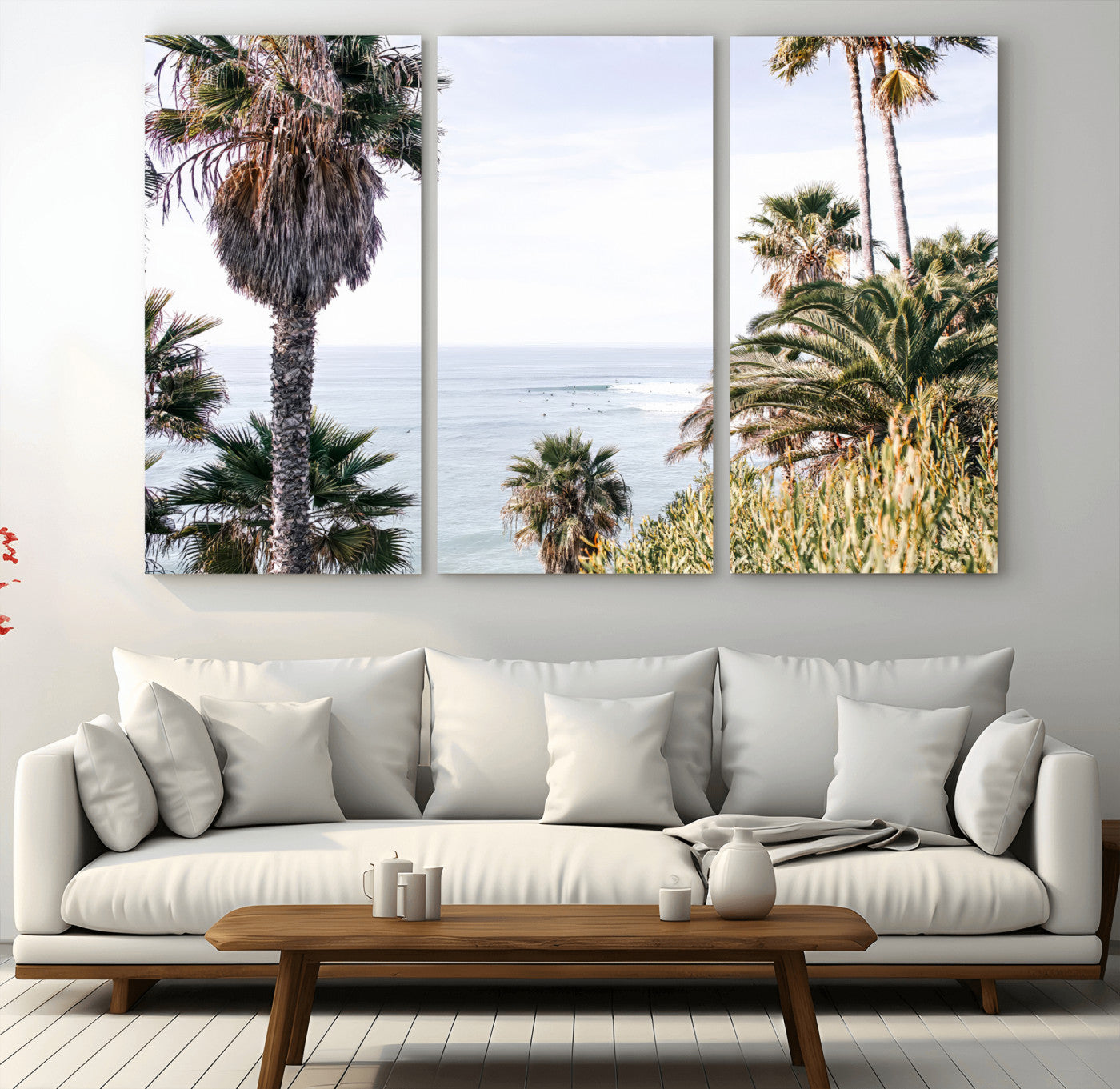 Scenic coastal view with tall palm trees overlooking a calm ocean, soft blue waves, and surfers in the distance, creating a peaceful tropical vibe.
