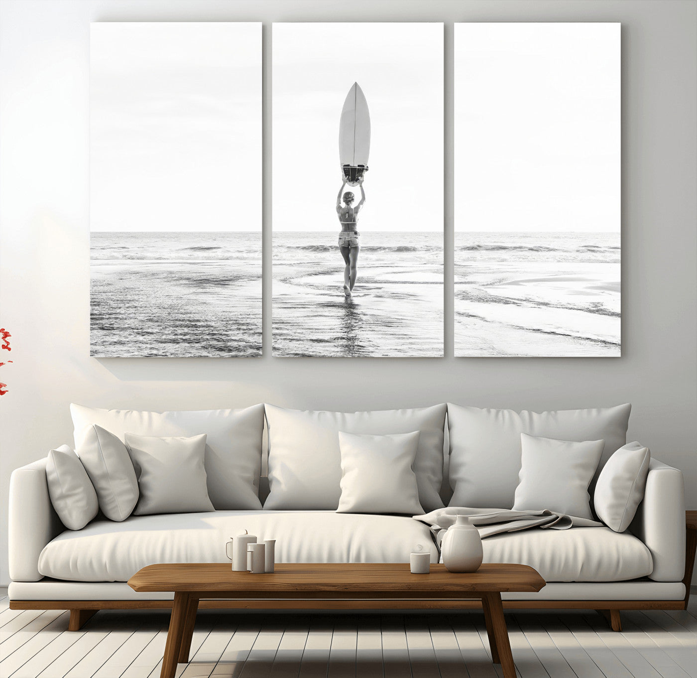 Black and white image of a female surfer holding a surfboard above her head while walking toward the ocean, creating a minimalist and bold coastal aesthetic.