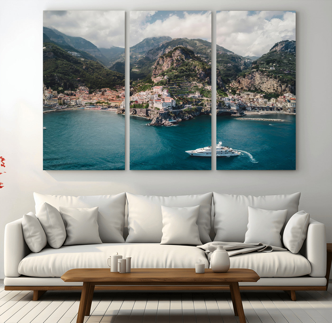 Aerial view of Amalfi Coast, Italy, with colorful hillside houses, lush green mountains, and a luxury yacht sailing in turquoise waters.