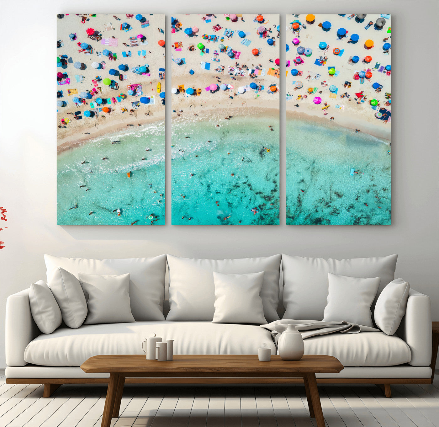 Aerial view of a vibrant beach filled with colorful umbrellas and people enjoying the turquoise ocean, capturing a lively summer vacation scene.