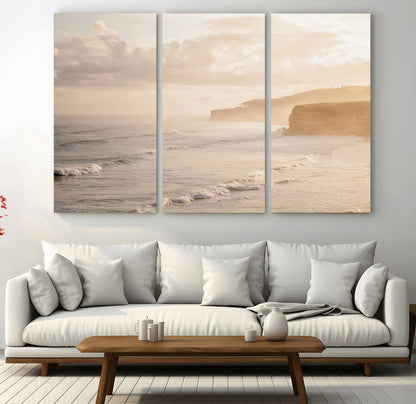 Golden hour seascape with misty cliffs and gentle waves rolling towards the shore, capturing a tranquil and warm coastal atmosphere.