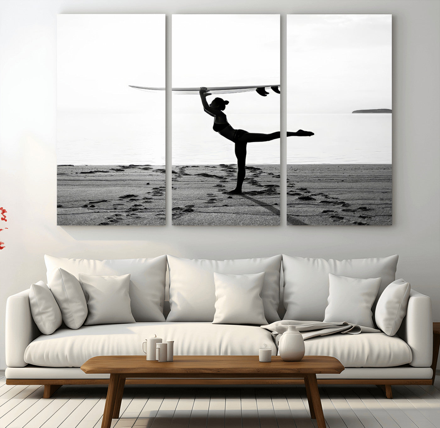 A woman balances a surfboard on her head while striking a yoga pose on the beach, silhouetted against a calm ocean horizon.