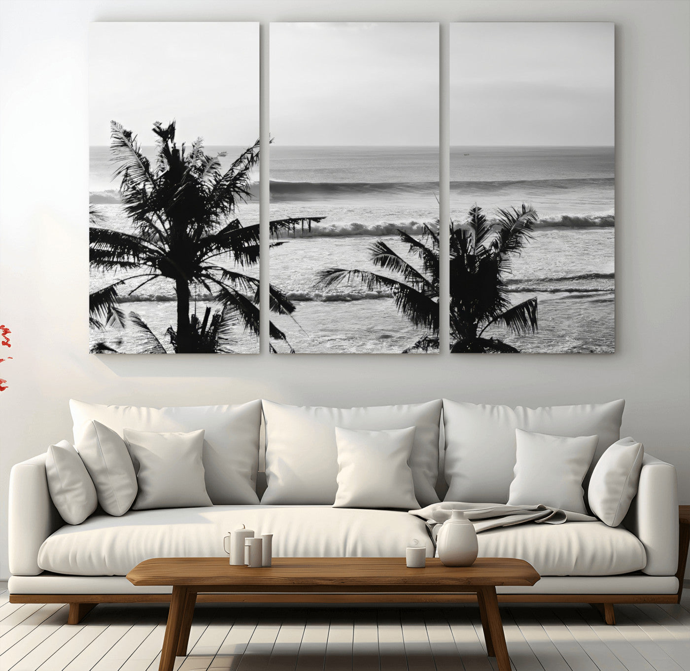 Black and white view of ocean waves crashing on a tropical coastline, framed by silhouetted palm trees under a vast, open sky.