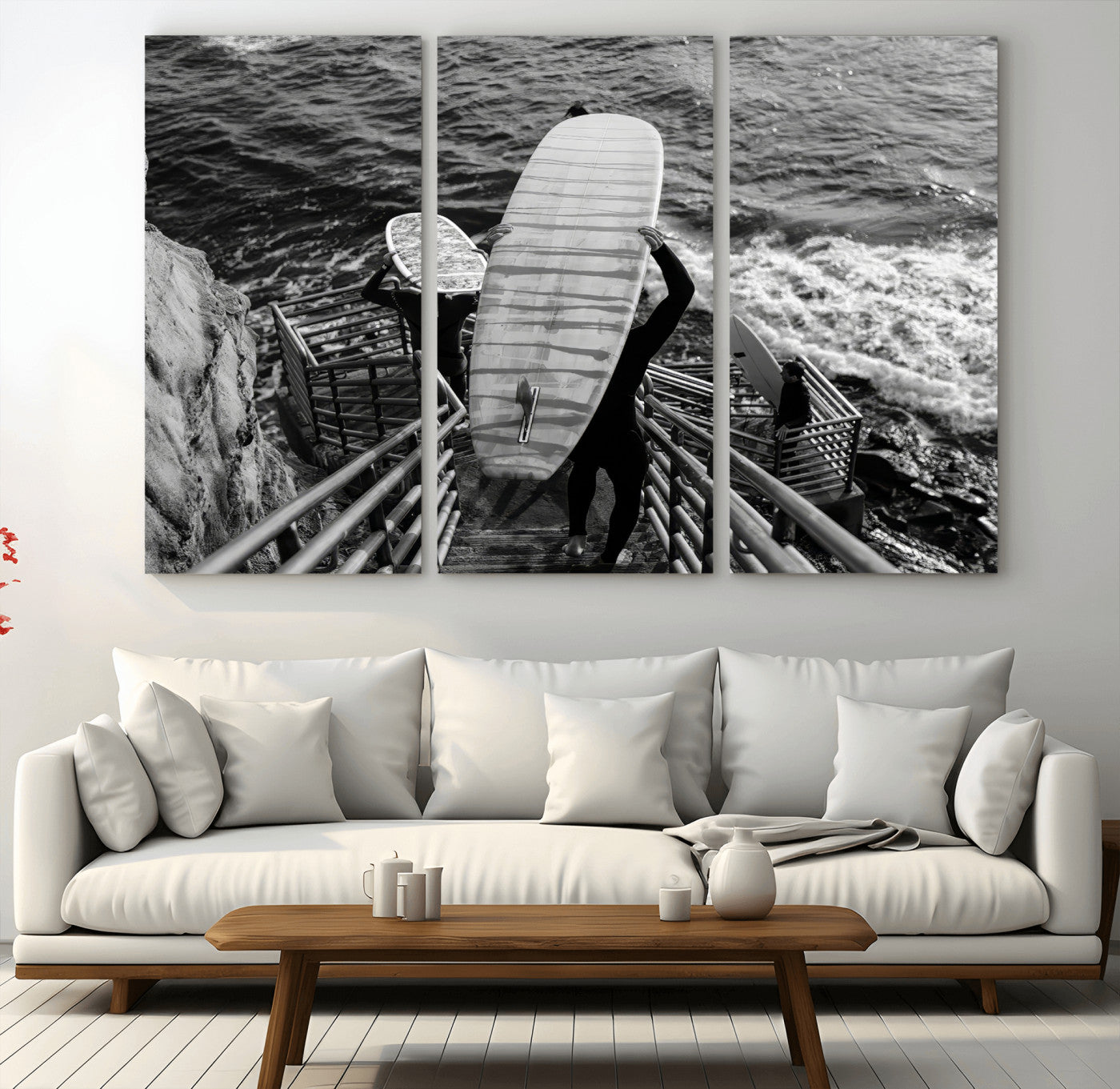 Black and white photo of surfers carrying boards down a rugged cliffside stairway, capturing a bold and adventurous coastal scene.